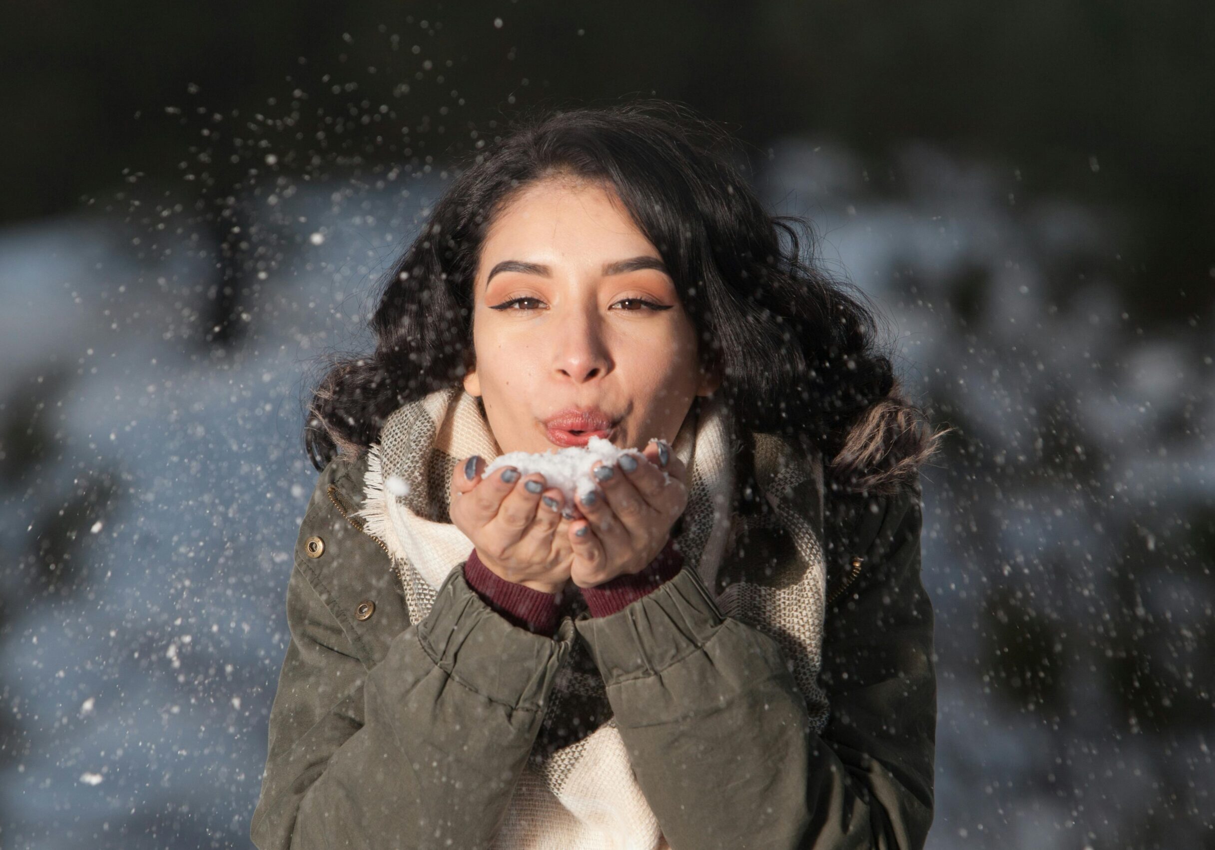 Image of a woman blowing snow out of her hands.