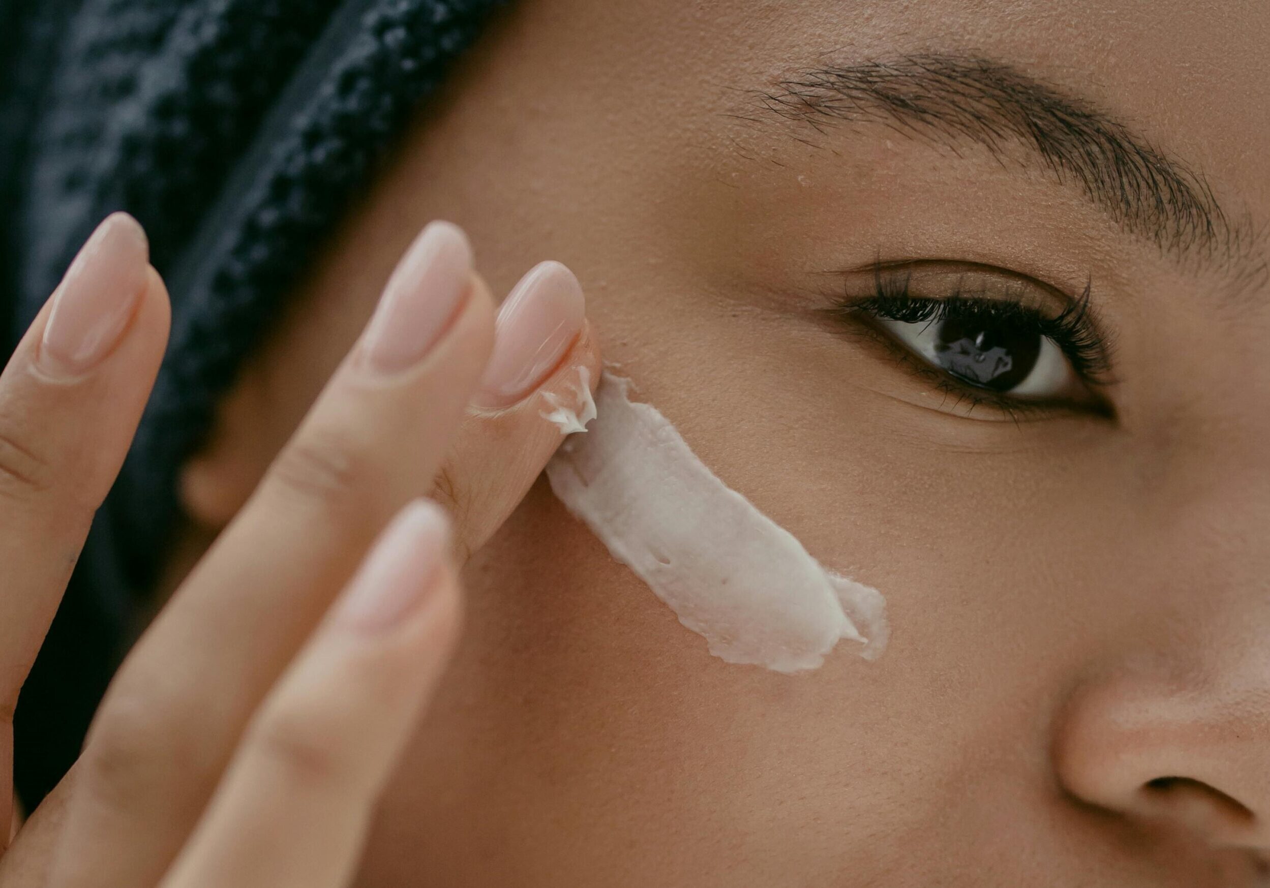 Image of a woman putting a skincare product on her cheek.