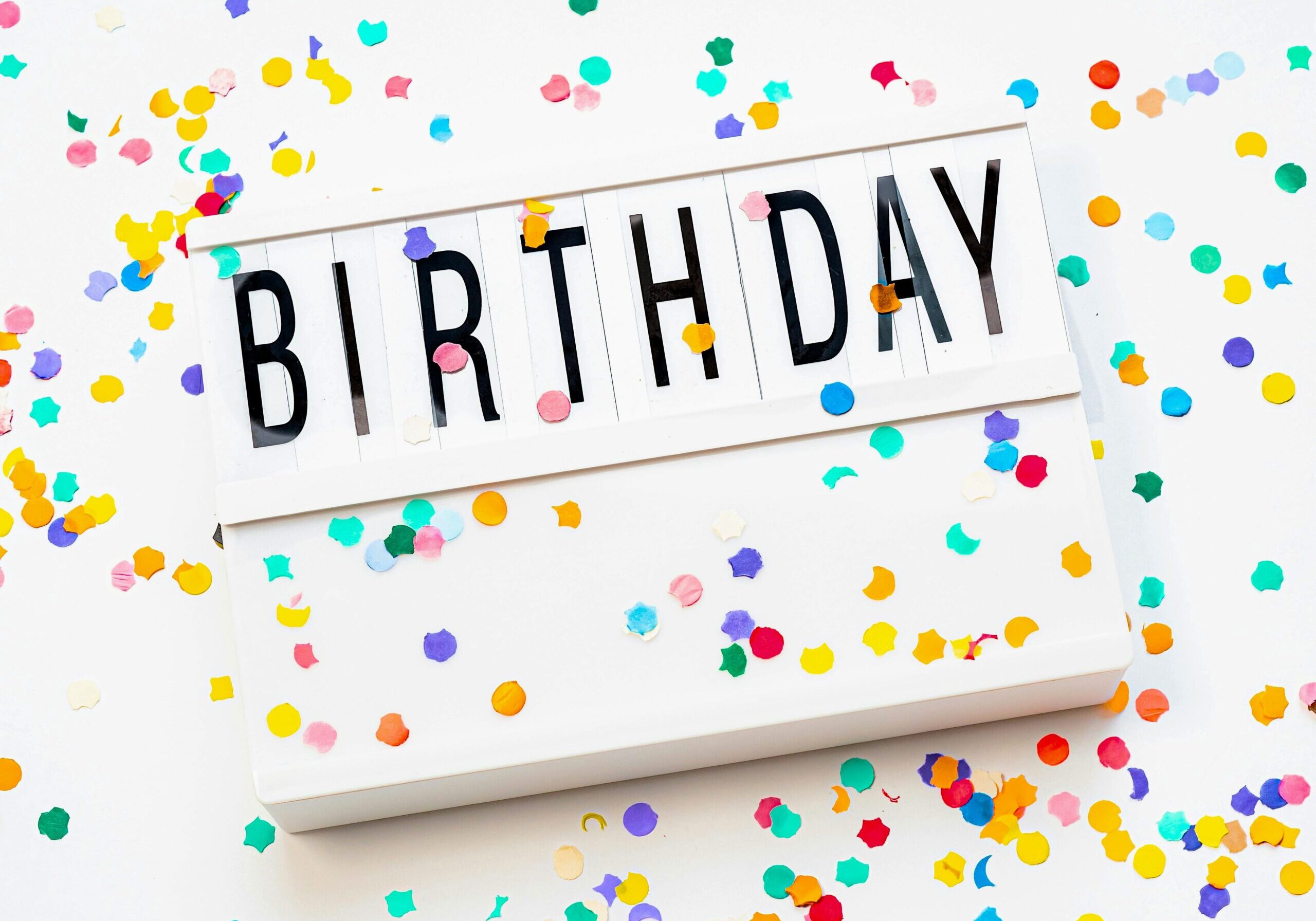 Image of a sign with "birthday" on it and confetti everywhere.