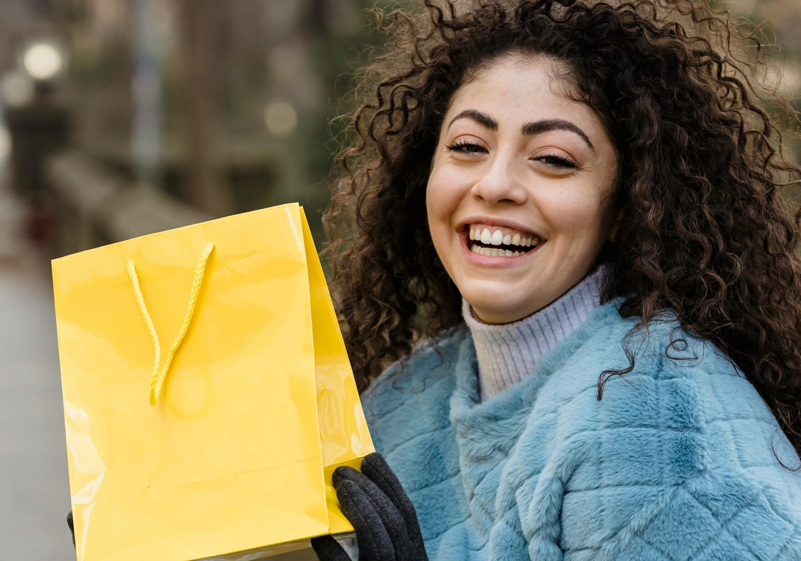 Image of a woman smiling and holding a bag.