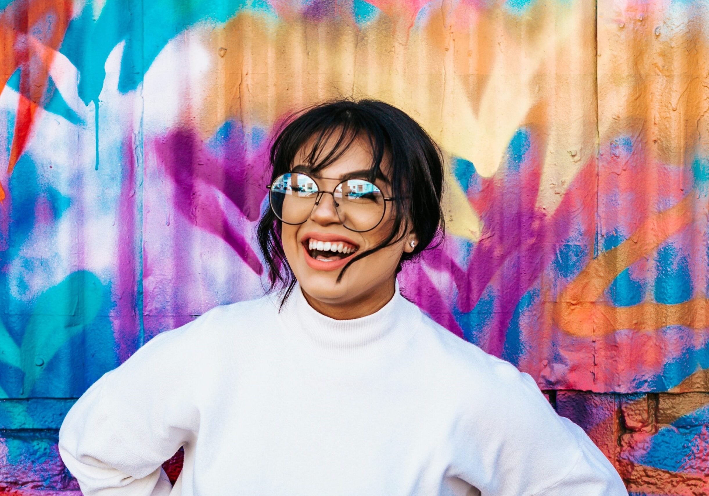 Image of a woman smiling in front of an abstract mural.